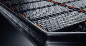 Close-up of a lithium-ion EV battery pack with orange high-voltage connectors on a black background
