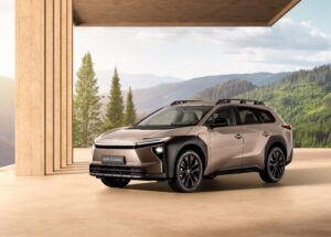 Toyota bZ4X Touring electric SUV in bronze, front three-quarter view with forested hills behind